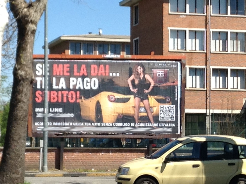 Rossa di rabbia per il cartellone sessista. Il titolare replica: “mai più pubblicità ad Alessandria”