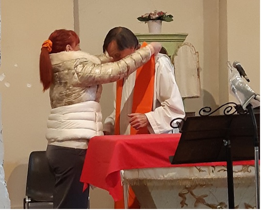 Sulle spalle di Don Ivo la stola arancione per dire no alla violenza